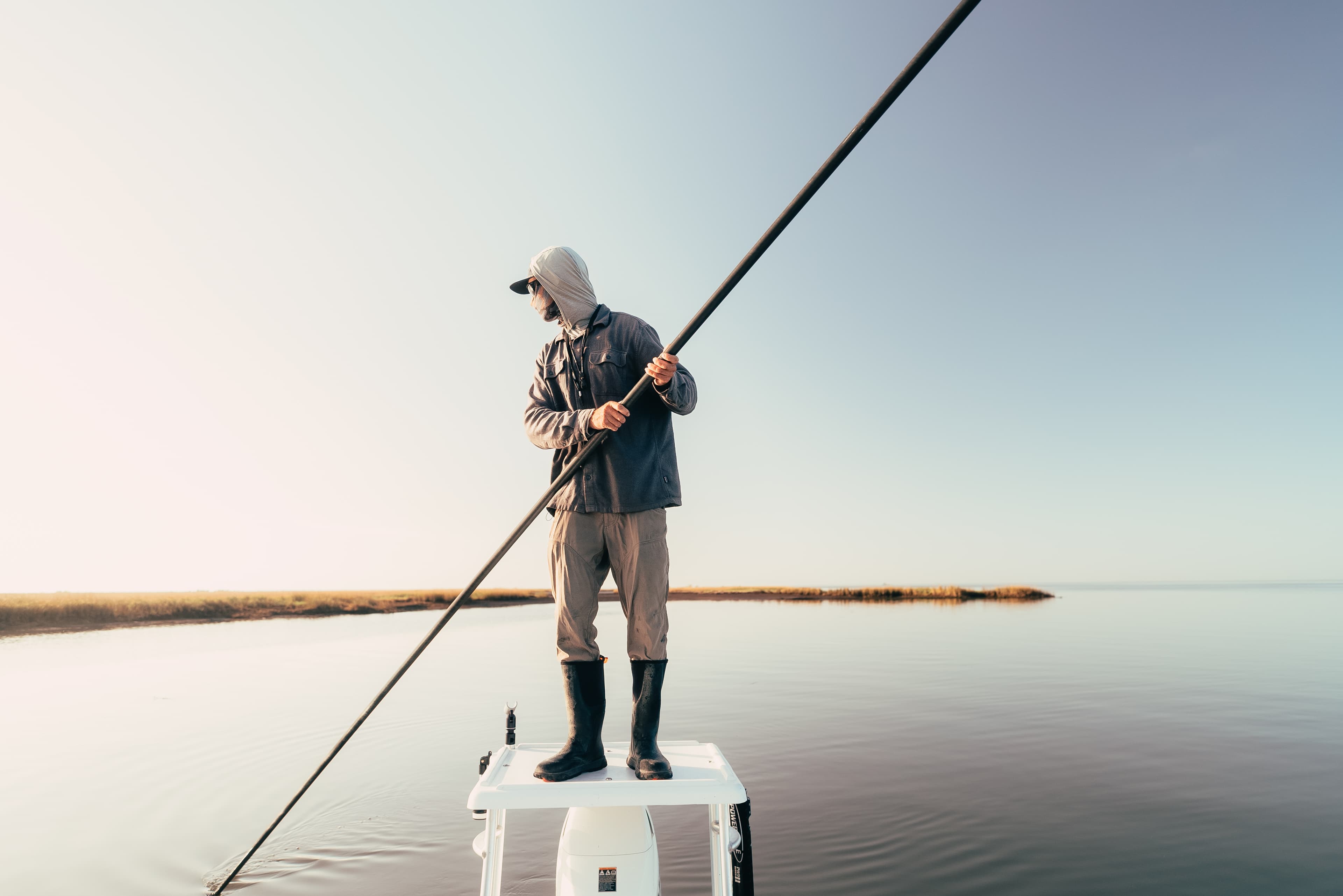 Angler fly fishing from a skiff on the Louisiana coastal marsh for redfish.
