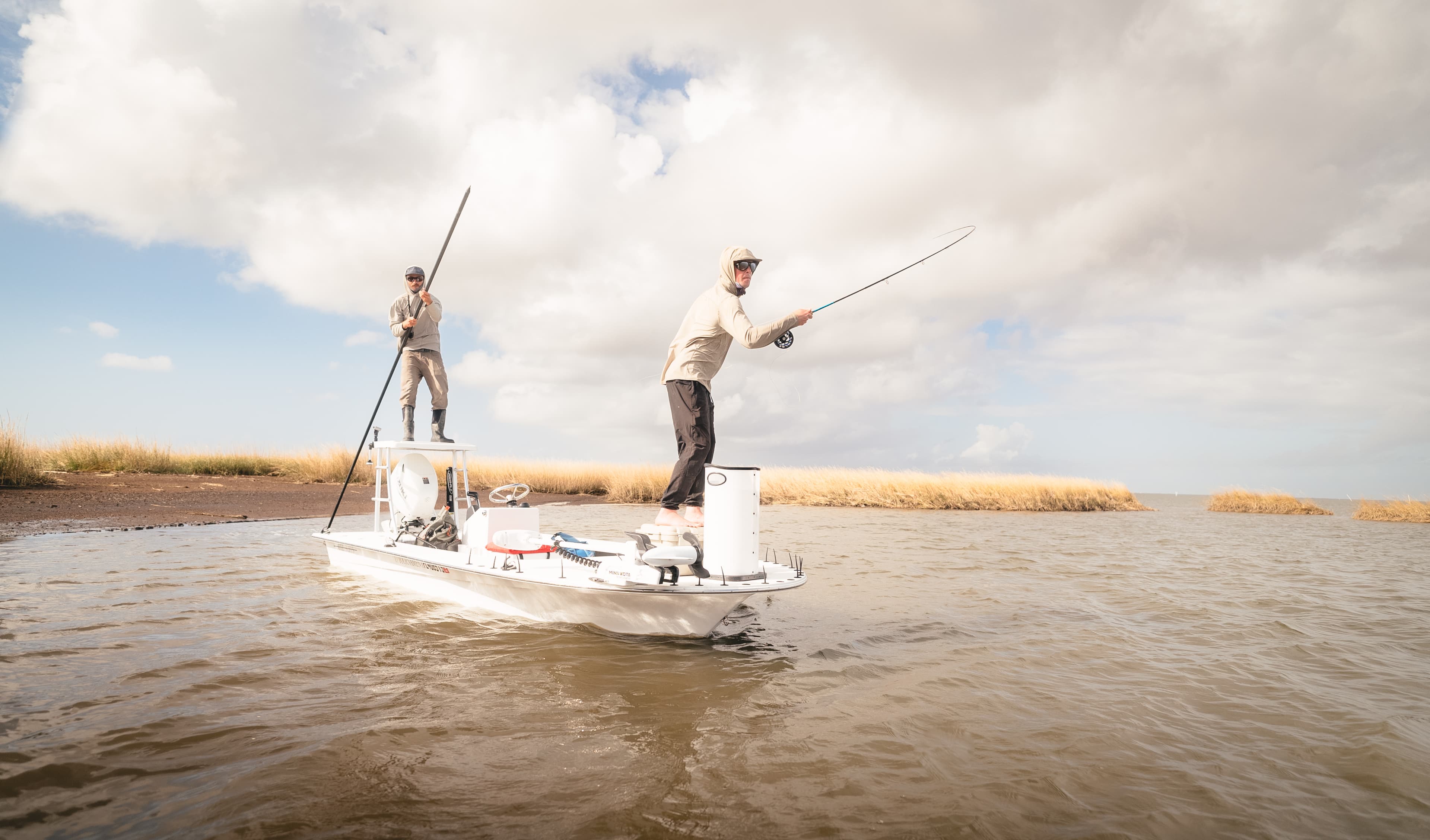 Angler casting a fly to redfish from a skiff in the Louisiana coastal marsh